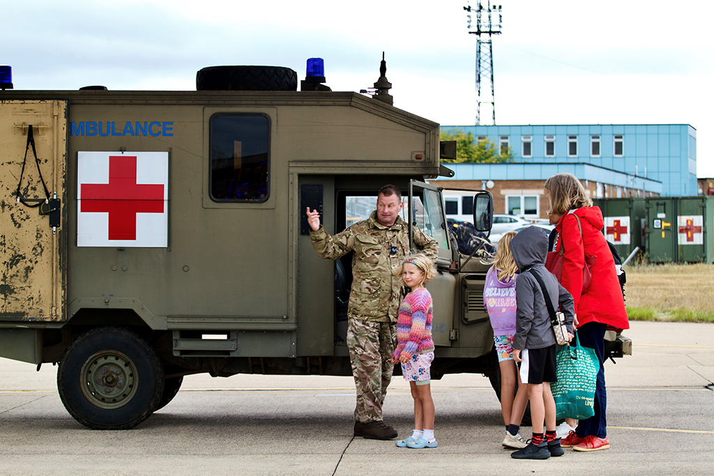 A family, standing in front of a field ambulance, having a look around.